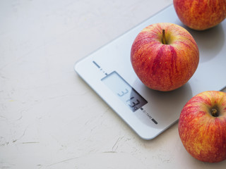 Red apples on kitchen scales on white background. Product weighing