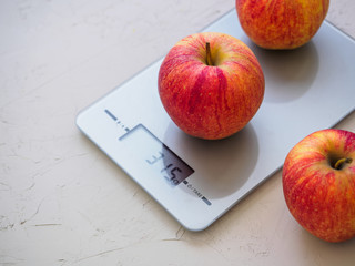 Red apples on kitchen scales on white background. Product weighing