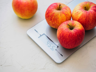 Red apples on kitchen scales on white background. Product weighing