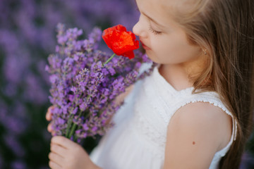 Happy cute little girl in lavender field holding bouquet of purple flowers.