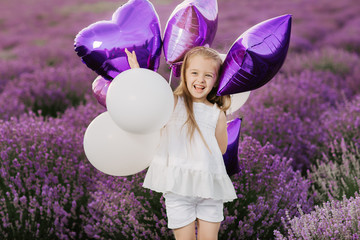 Happy cute little girl in lavender field with purple balloons. Freedom concept.