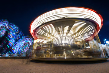 Abstract, long exposure shot of spinning Children's vintage Carousel at an amusement park in the evening and night illumination. Beautiful, bright carousel in Alicante, Spain  
