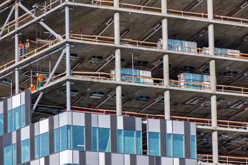 New residential and office block buildings being constructed. Industrial building site. Workers putting windows in under construction skyscraper