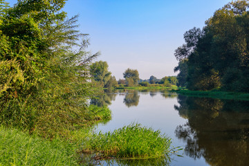 View of river surface on a background of blue sky at sunrise. River landscape on a summer morning