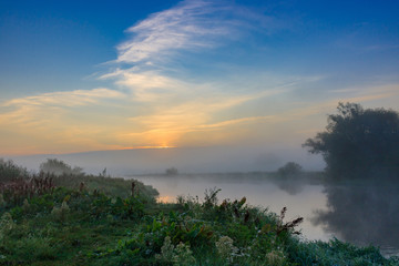 Sunrise on the river in early morning on a blue sky background. River landscape in summer morning