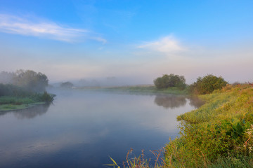 Fototapeta na wymiar River with fog above surface. River landscape at sunny summer morning
