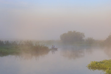 Obraz na płótnie Canvas Two young men catching fish from an inflatable boat on the river in early morning. River landscape