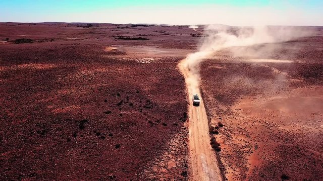A four wheel drive travelling fast on a very dry dusty dirt track in outback South Australia. Aerial shot tracking above with other cars behind. Extreme tourism in remote areas.