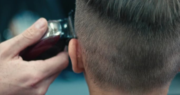 Barder cutting boys hair with electric razor