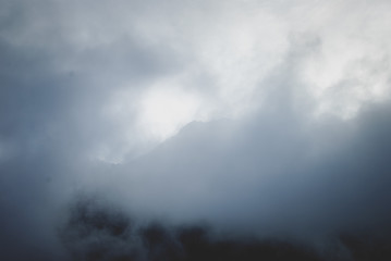 White summit of mountain covered with snow. Dense spring fog in Austrian Alps. Vintage colors