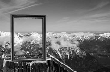 Monochromatic (black and white) spectacular view of clear sky and snowy mountain peaks through picture frame in Austrian Alps. Five Fingers, Obertraun