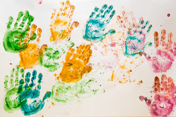 Bright children's drawing with finger paints. Prints of colorful palms on white paper.
