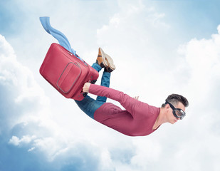 Crazy man in goggles flies in the sky with a red suitcase with fluttering clothes. Concept is...