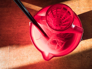 soaking a mop in red bucket of water