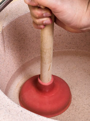 man clears water in kitchen sink pipe by plunger