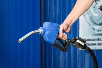 Fuel pump in hand man on blue background. Petrol station. Holding fuel nozzle. 