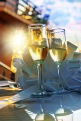 Romantic wedding scene with champagne glasses against sunset light, outdoor