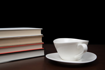 books stacked on the desk with a cup of coffee.