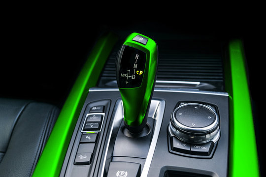 Green Automatic gear stick of a modern car. Modern car interior details. Close up view. Car detailing. Automatic transmission lever shift. Black leather interior with stitching.