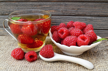 Raspberry tea with fresh picked berries in a glass transparent cup on old wooden table.Natural herbal beverage.