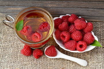 Raspberry tea with fresh picked berries in a glass transparent cup on old wooden table.Natural herbal beverage.Top view.