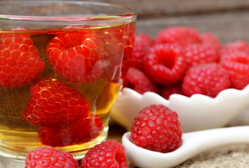 Raspberry tea with fresh picked berries in a glass transparent cup on old wooden table.Natural herbal beverage.Selective focus.