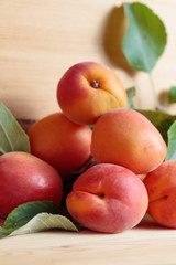 Apricots with leaves on a wooden table.