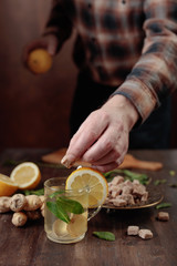 Ginger tea with brown sugar , lemon and mint on old wooden table .