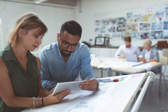 Executives discussing over digital tablet on drafting table