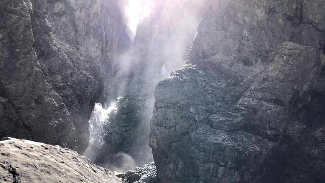 Slow motion shot of water from a mountain water fall going down with water drops all over the camera