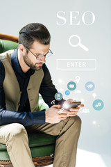 stylish bearded developer using smartphone, with SEO search and icons