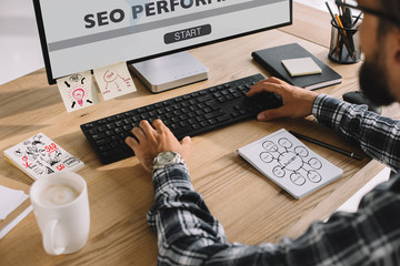 cropped shot of seo manager in plaid shirt using computer at workplace