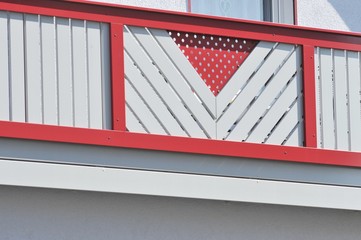 Rot-weißes Holzgeländer am Balkon eines Wohnhaus