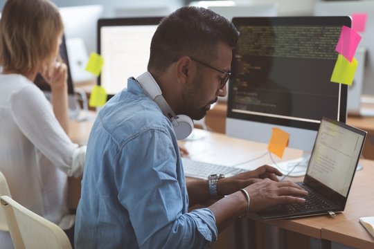 Male executive using laptop at desk