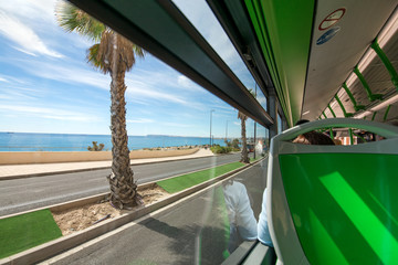 View of palm trees and seaside from public transportation bus. People are going to vacation,...