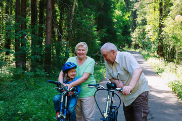 Obraz premium active senior couple with little granddaughter on bikes in nature