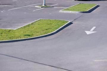 Obraz premium Newly made parking lot next to shopping mall in city centre with green areas. Arrows and signs on asphalt showing directions