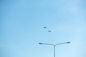 Military helicopters flying in the sky over a city and crowded event, taking photos, filming from above on clear blue sky background. An Isolated helicopter. Team of rescuers searching for lost people