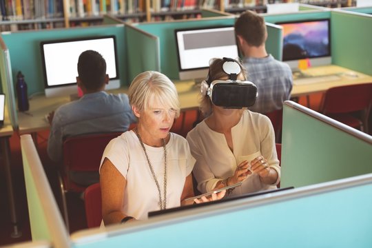 Female executives using virtual reality headset and digital