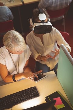 Female executives using virtual reality headset and digital