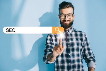 successful developer in checkered shirt pointing at SEO search bar