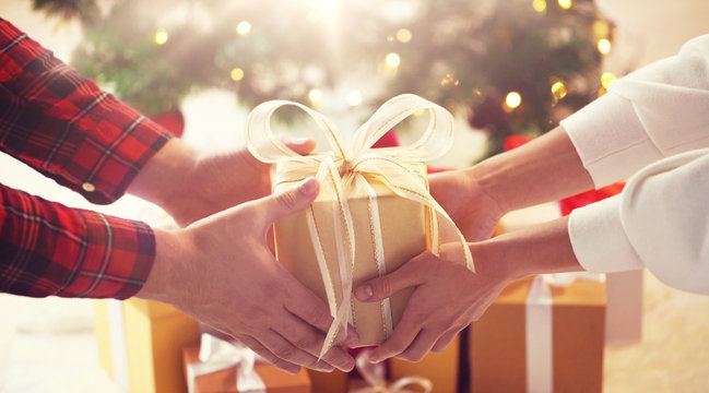 holidays, presents, new year and celebration concept - close up of couple hands giving and receiving christmas gift box