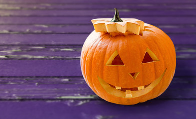 holidays, halloween and decoration concept - close up of carved pumpkin over ultra violet shabby...