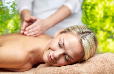 Obraz na płótnie Canvas beauty, wellness and relaxation concept - beautiful young woman lying having back massage in spa over green natural background