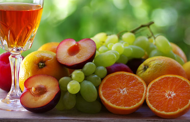 wineglass, citric fruits, grapes and plums