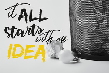 light bulb with crumpled papers in office trash bin on white with "it all starts with an idea" inspiration