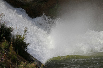 Splashes and spray from waterfall. Big water splash in lake after diving. Splash water on the river, beautiful colorful bright splash. Dam waterfalls with big diving splashes. Water splash background.