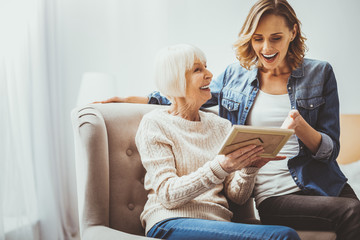 Sincere emotions. Delighted mature woman expressing positivity while demonstrating old photo