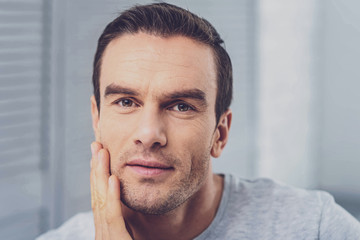 Facial wrinkles. Pleasant handsome man with facial wrinkles feeling wonderful while standing in light room at home