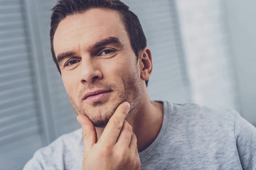 Obraz premium Bristle chin. Pleasant handsome mature man touching his bristle chin while feeling thoughtful realizing some surprising facts